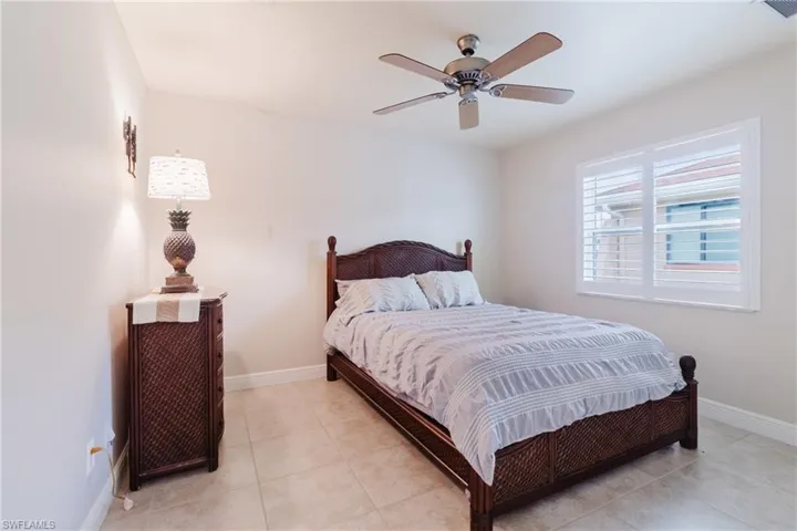 Bedroom with light tile patterned floors, baseboards, ceiling fan, and visible vents