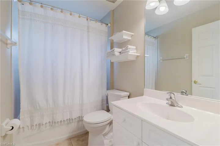 Bathroom featuring toilet, a shower with shower curtain, tile patterned flooring, and vanity