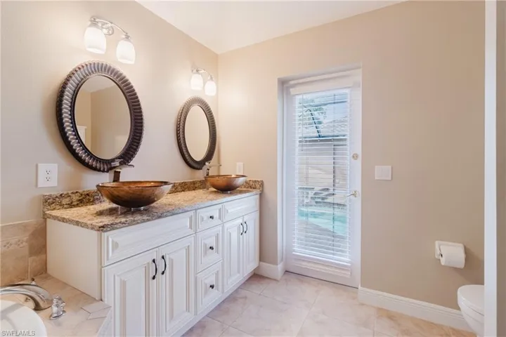 Bathroom with toilet, tile patterned floors, double vanity, and a sink