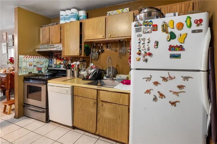 Kitchen featuring light tile patterned floors, sink, and white appliances