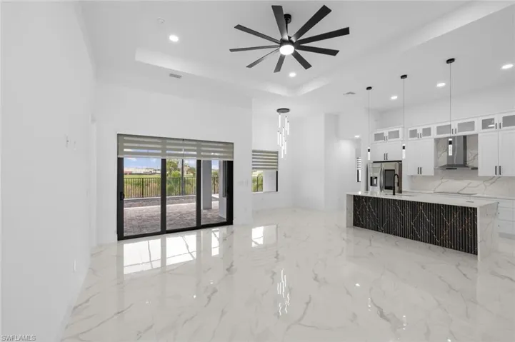 Unfurnished living room with sink, light tile patterned flooring, ceiling fan, and a raised ceiling