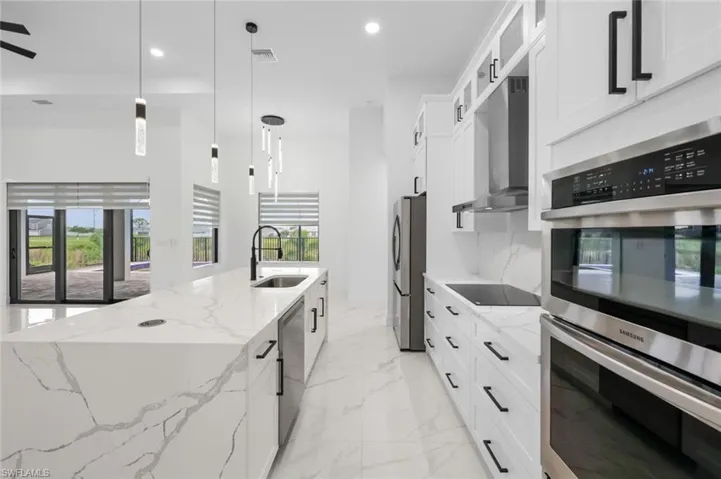 Kitchen featuring a healthy amount of sunlight, appliances with stainless steel finishes, sink, and wall chimney range hood