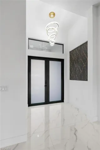 Unfurnished room featuring tile patterned floors, french doors, and a chandelier