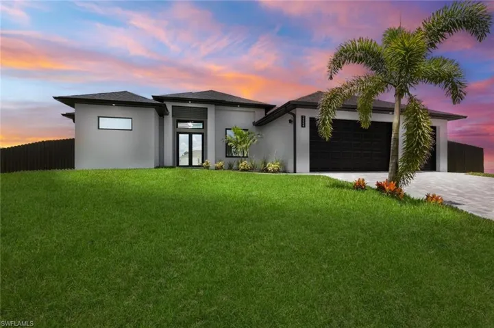 View of front of property featuring a garage and a yard