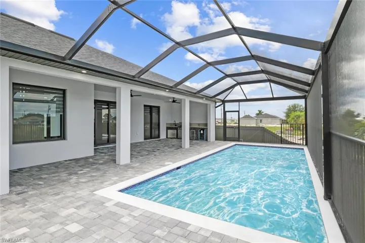 View of pool with a patio area, ceiling fan, and glass enclosure