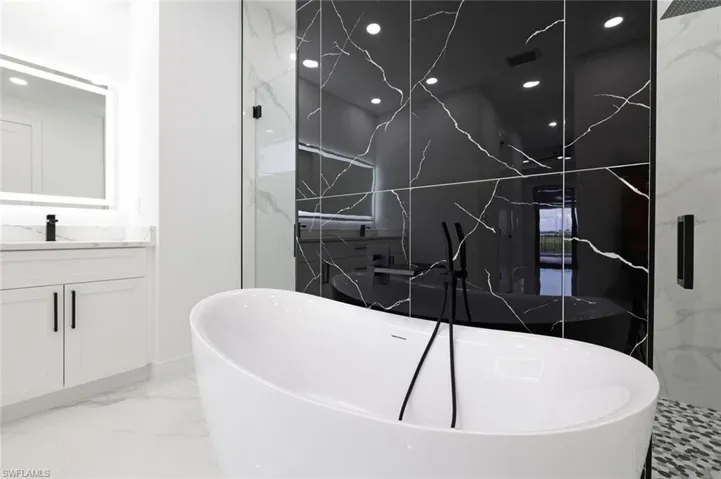 Bathroom featuring tile patterned flooring, shower with separate bathtub, and vanity