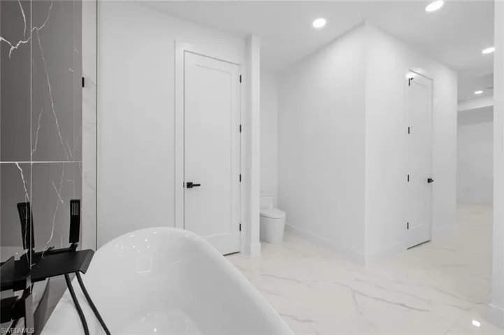Bathroom with tile patterned floors, tile walls, a bathing tub, and toilet