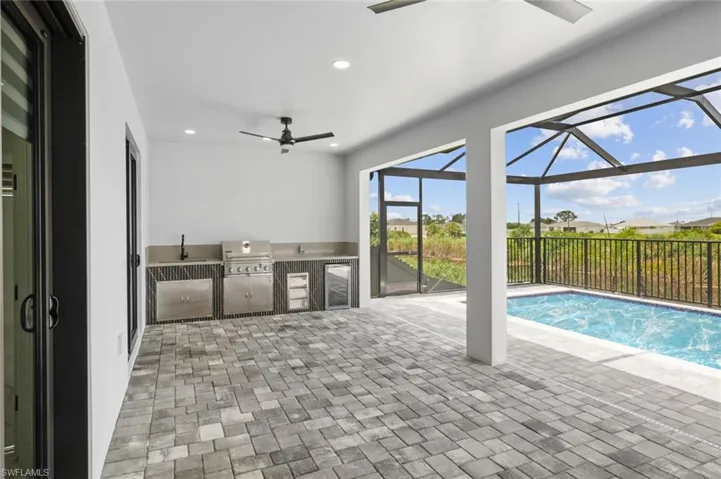 View of swimming pool featuring grilling area, sink, and ceiling fan
