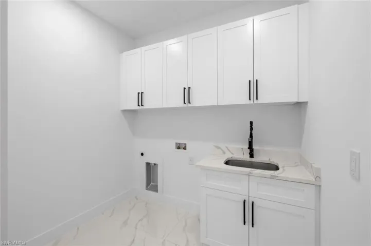 Laundry area with light tile patterned flooring, sink, electric dryer hookup, cabinets, and hookup for a washing machine