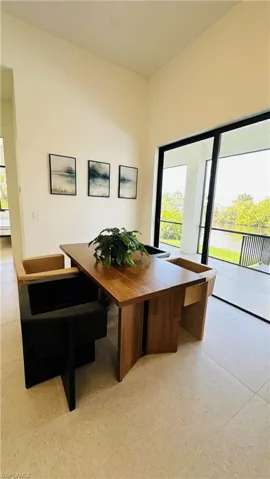 Open-concept room featuring high ceilings, light-toned tile flooring, and a full wall of sliding glass doors