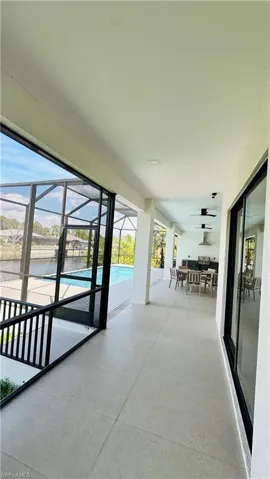 Expansive screened lanai featuring a swimming pool, tiled flooring, an outdoor kitchen with stainless steel appliances, and ceiling fans