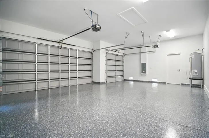 Garage with electric panel, electric water heater, and a garage door opener