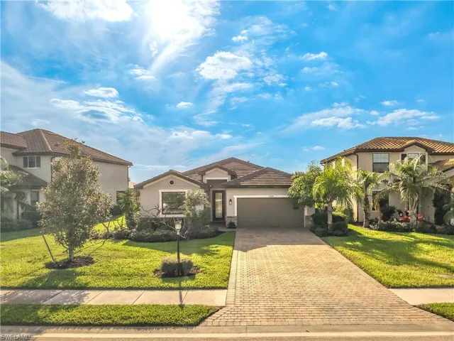 View of front of property with an attached garage, a front yard, driveway, and stucco siding