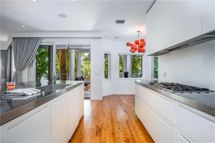 Kitchen with stainless steel counters, white cabinets, stainless steel gas stovetop, and light hardwood / wood-style flooring
