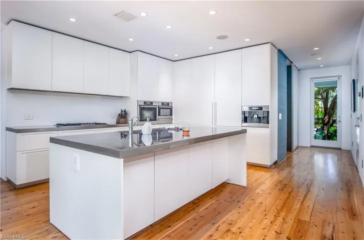 Kitchen with white cabinetry, light hardwood / wood-style flooring, and a center island with sink