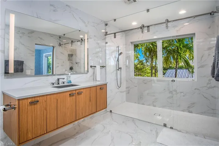 Bathroom with vanity, a wealth of natural light, and tiled shower