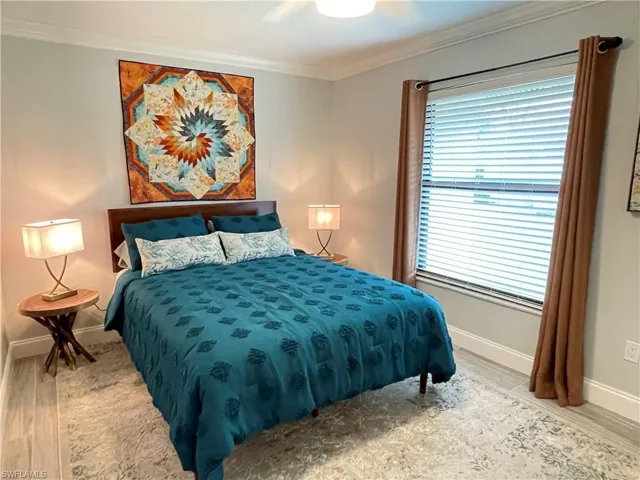 Bedroom with crown molding, ceiling fan, and light wood-type flooring