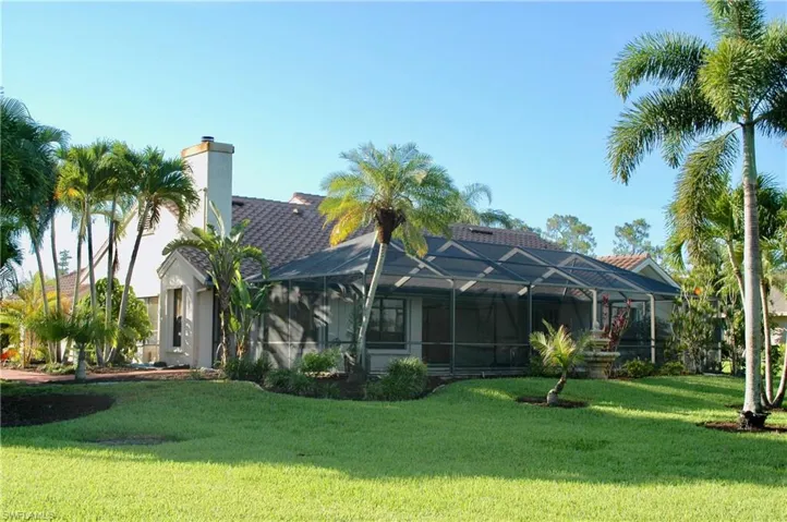 Back of house featuring a yard and a lanai