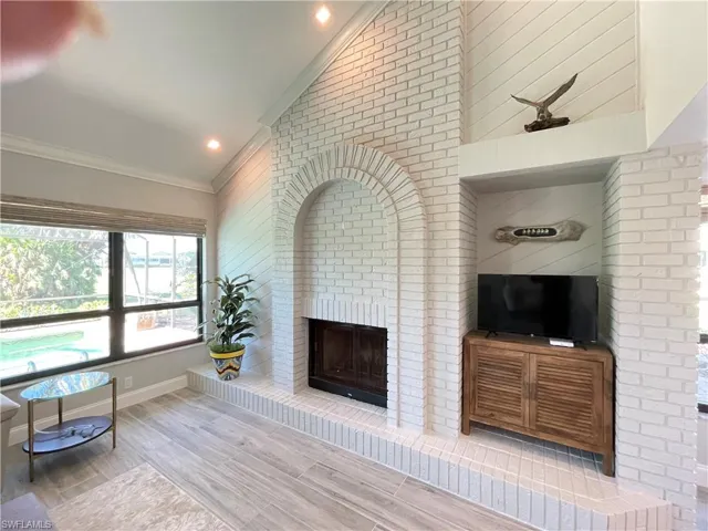 brick fireplace, vaulted ceiling, and ornamental molding