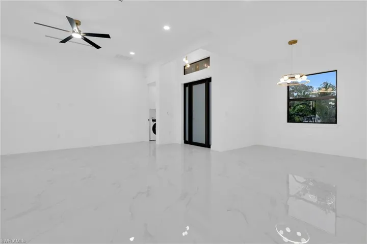 Spare room with light marble finish floors, a chandelier, recessed lighting, washer / dryer, and ceiling fan