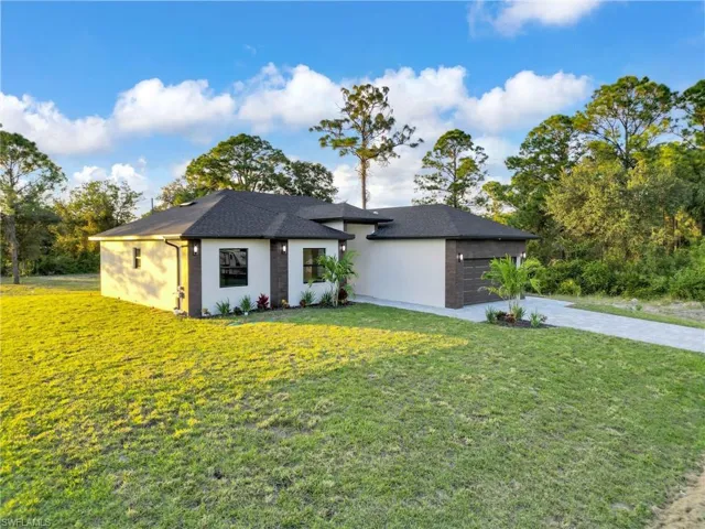 View of front of home with driveway, a front yard, stucco siding, an attached garage, and a shingled roof