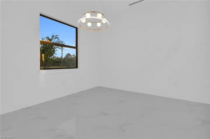 Empty room with marble look tiles and a chandelier