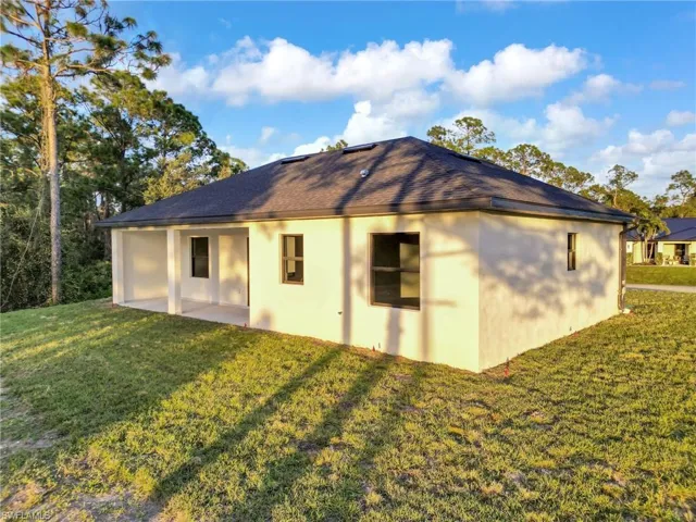 Back of house with a lawn, stucco siding, and a patio area