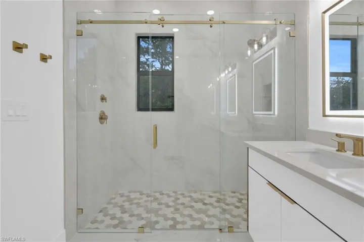 Bathroom featuring vanity and a marble finish shower