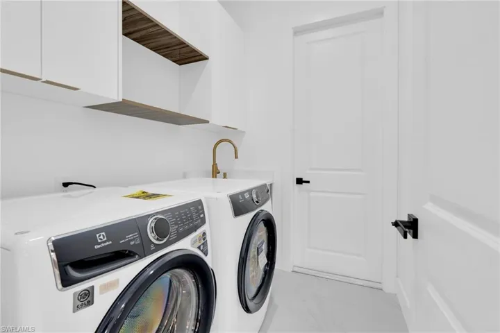 Laundry room featuring light marble finish flooring, separate washer and dryer, and cabinet space
