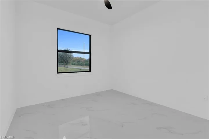 Spare room featuring marble look tiles and baseboards