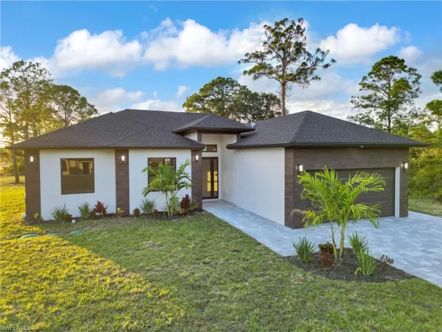 View of front of property with a garage, a front lawn, stucco siding, and a shingled roof
