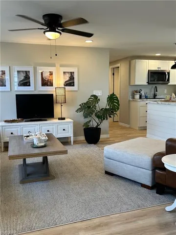 Living room featuring ceiling fan, sink, and light hardwood / wood-style floors