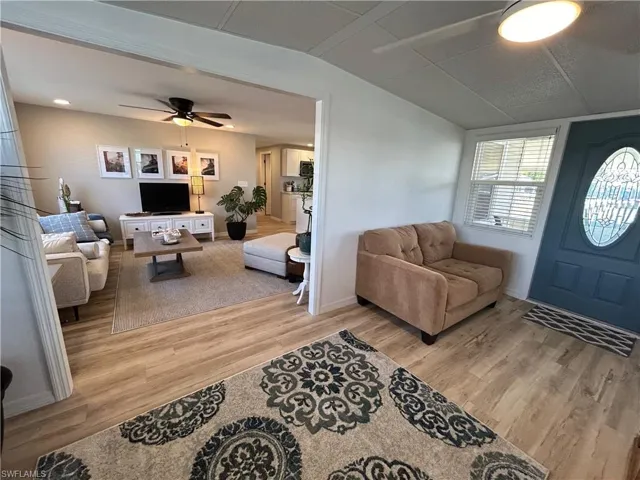 Living room featuring light hardwood / wood-style floors, vaulted ceiling, and ceiling fan