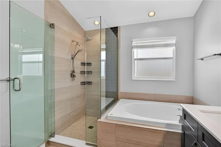 Sleek bathroom featuring a spacious walk-in shower with glass enclosure, light-toned horizontal tile, and a rainfall showerhead