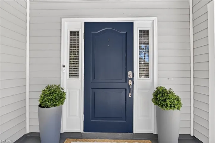 Navy blue paneled entry door with sidelights, white trim, and light grey horizontal siding