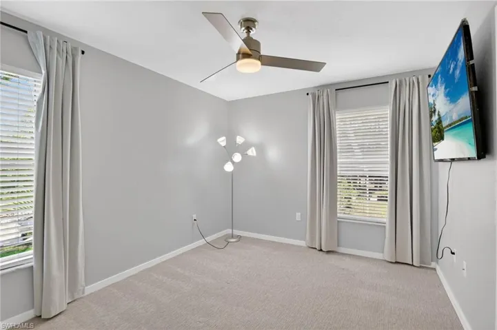 Spacious room featuring neutral carpeting, light gray walls, and white window blinds