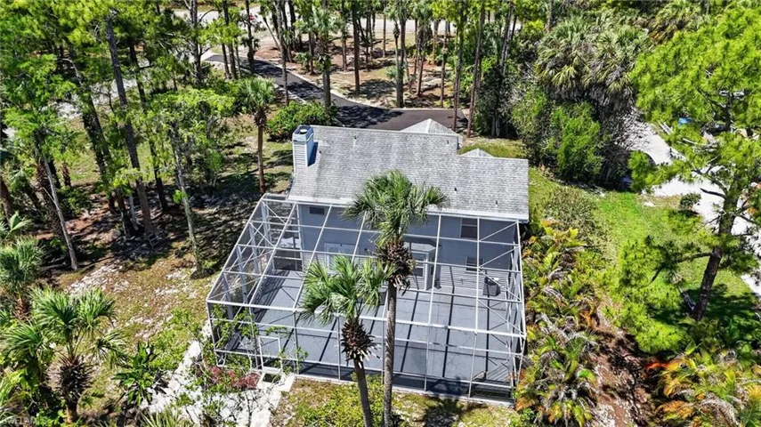 Screened enclosure with paved patio, surrounded by mature trees and natural landscaping