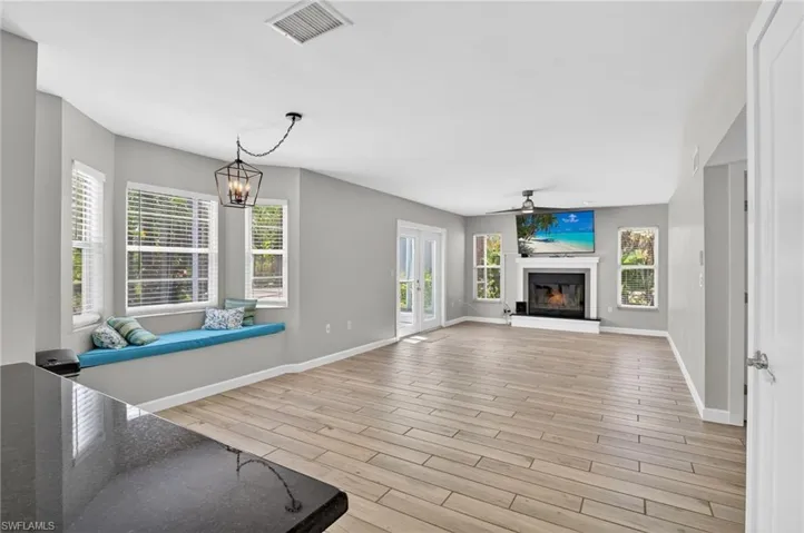 Spacious living area featuring wood-finish flooring, a fireplace with a white mantel, and multiple windows