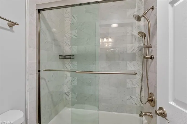 Shower-over-tub combination featuring a frameless glass enclosure with brushed nickel hardware