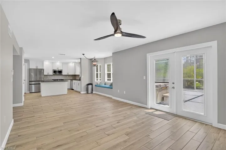 Spacious open-concept living area featuring wood-finish flooring and a contemporary ceiling fan