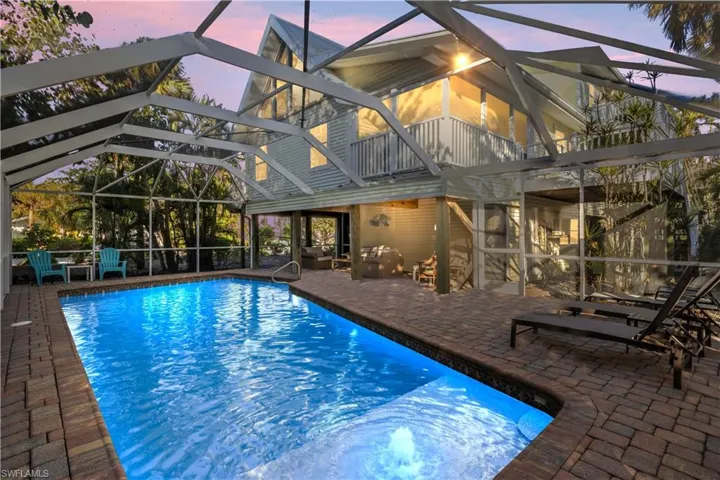 Pool at dusk with covered area and caged lanai.