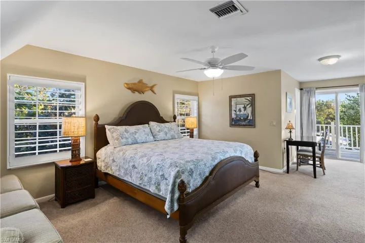 Bedroom featuring ceiling fan, light colored carpet, and access to outside deck.