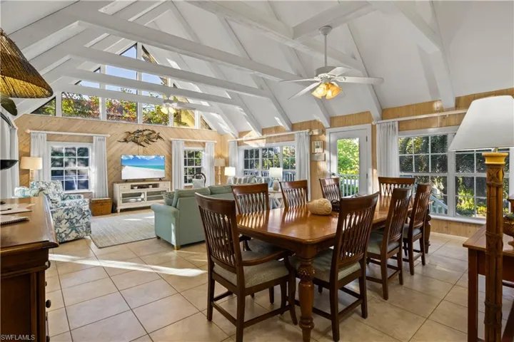 Dining room featuring  high vaulted beamed ceiling, ceiling fan, and wood walls.