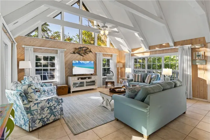 Large living room featuring vaulted ceiling with beams, a wealth of natural light, and ceiling fan.