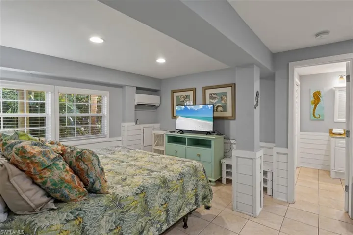 Efficiency Bedroom with a wall mounted AC and light tile patterned flooring.