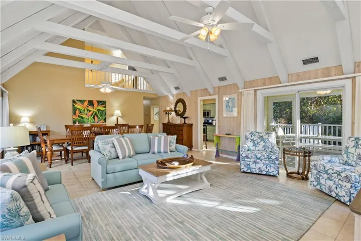 Living room with light tile patterned floors, high vaulted ceiling, ceiling fan, and beam ceiling.