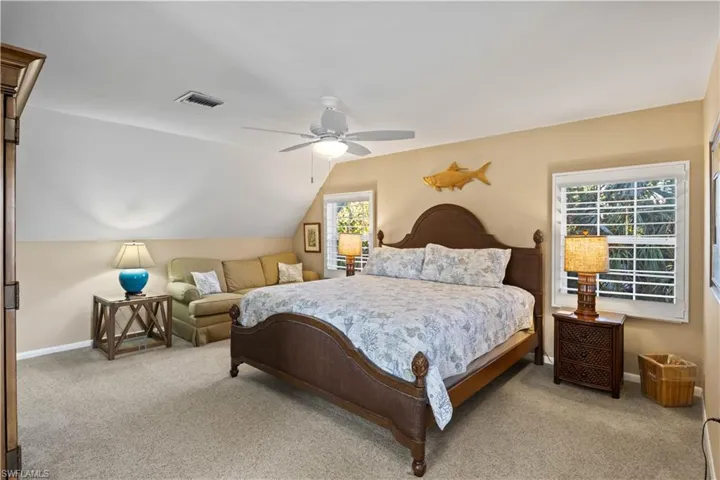 Carpeted bedroom with vaulted ceiling and private deck.