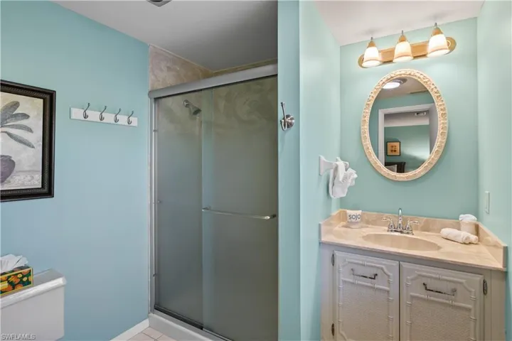 Private guest Bathroom featuring tile patterned flooring, vanity, and an enclosed shower.