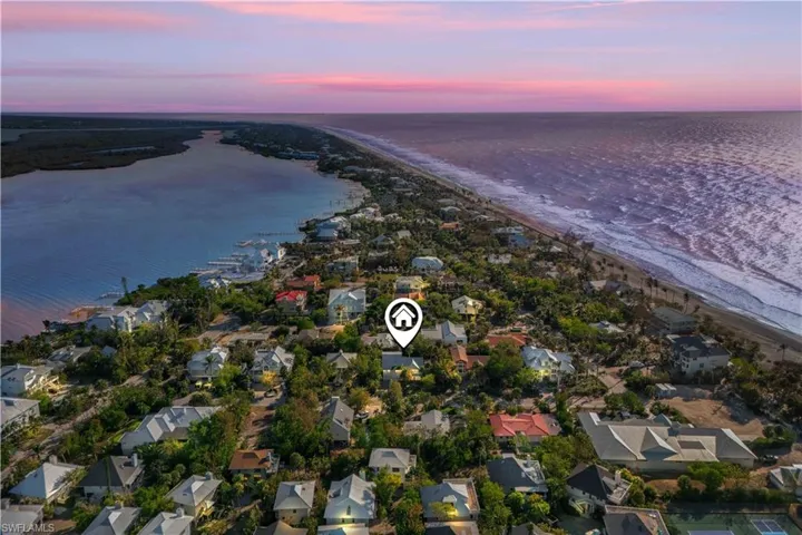 Aerial view at dusk with a water view and a view of the beach