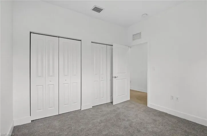 Unfurnished bedroom with multiple closets and carpet flooring